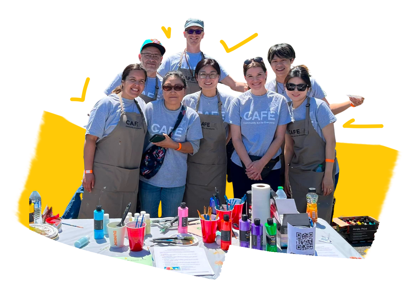 A group of CAFE volunteers posing in front of a chalk-art wall.