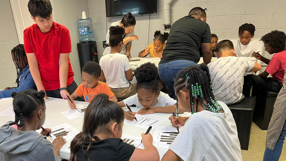 A room full of black and brown kids using markers to sketch up graphs on how they feel.