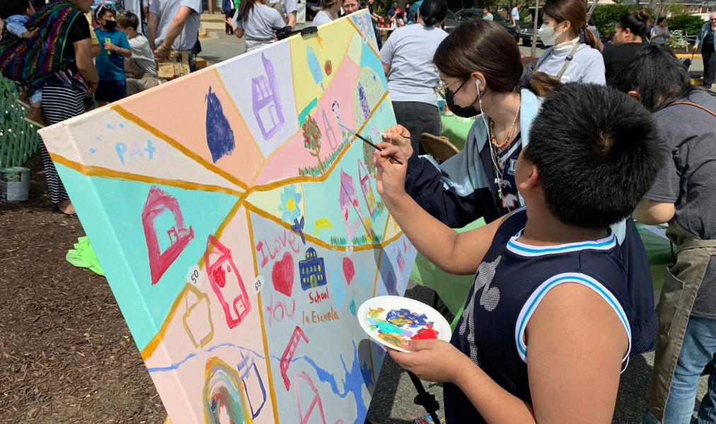 Two children painting on an open canvas.